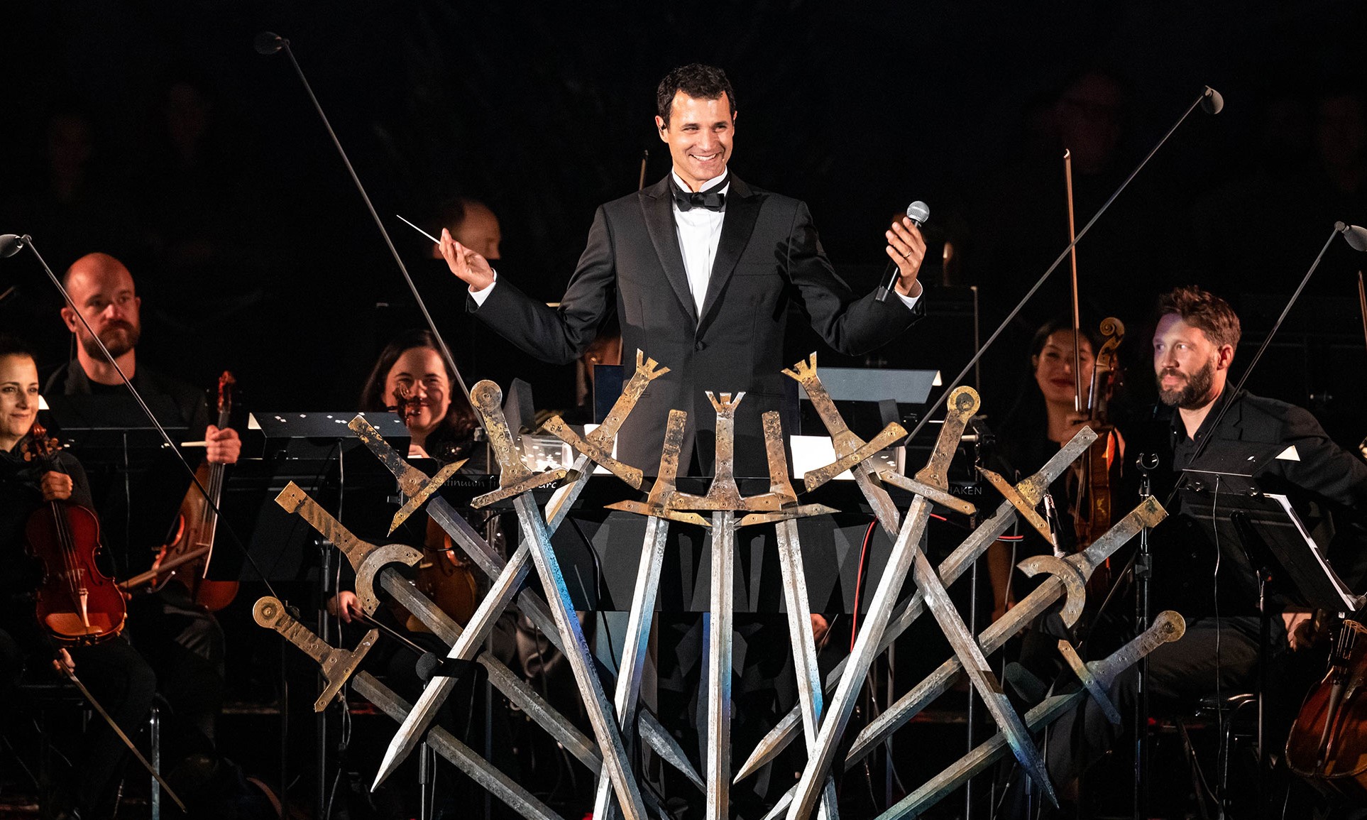 game of thrones'taki tahta benzeyen bir sahne süsünün arkasında ramin djawadi ve orkestrası yer alıyor