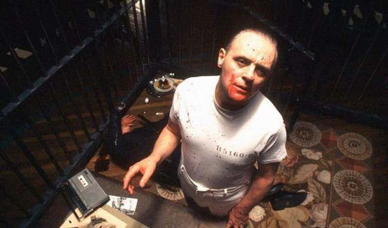 Hannibal Lecter vs. Joker: Hangisi Daha Tehlikeli Bir Psikopat? 15 hannibal parmaklıklarla çevrili bir hücrede yüzünde kan ile durmaktadır arkada ise yerde bir gardiyan yatmaktadır.